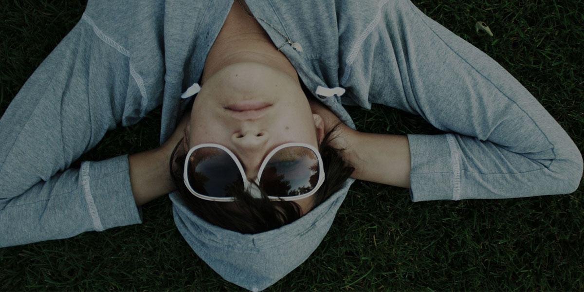 戴墨镜穿卫衣的男孩躺在草地上
